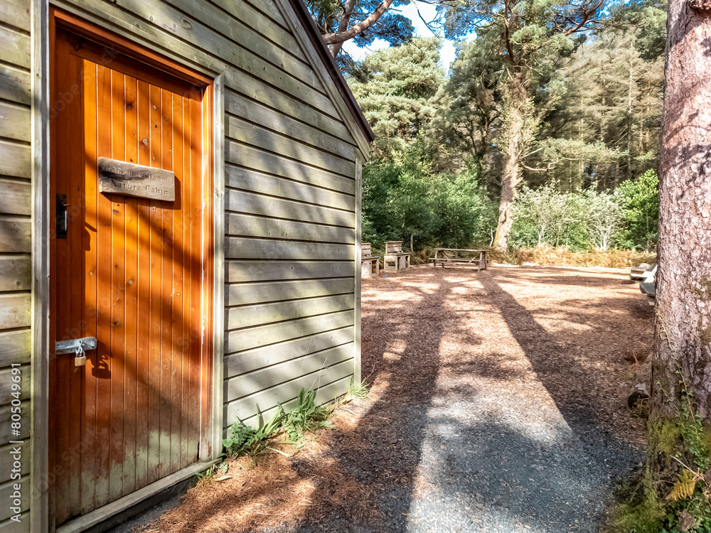 Wooden house in a forest in County Donegal - Ireland, Sign explaining in Irish and English: Nature Cabin Wooden house in a forest in County Donegal - Ireland, Sign explaining in Irish and English: Nature Cabin