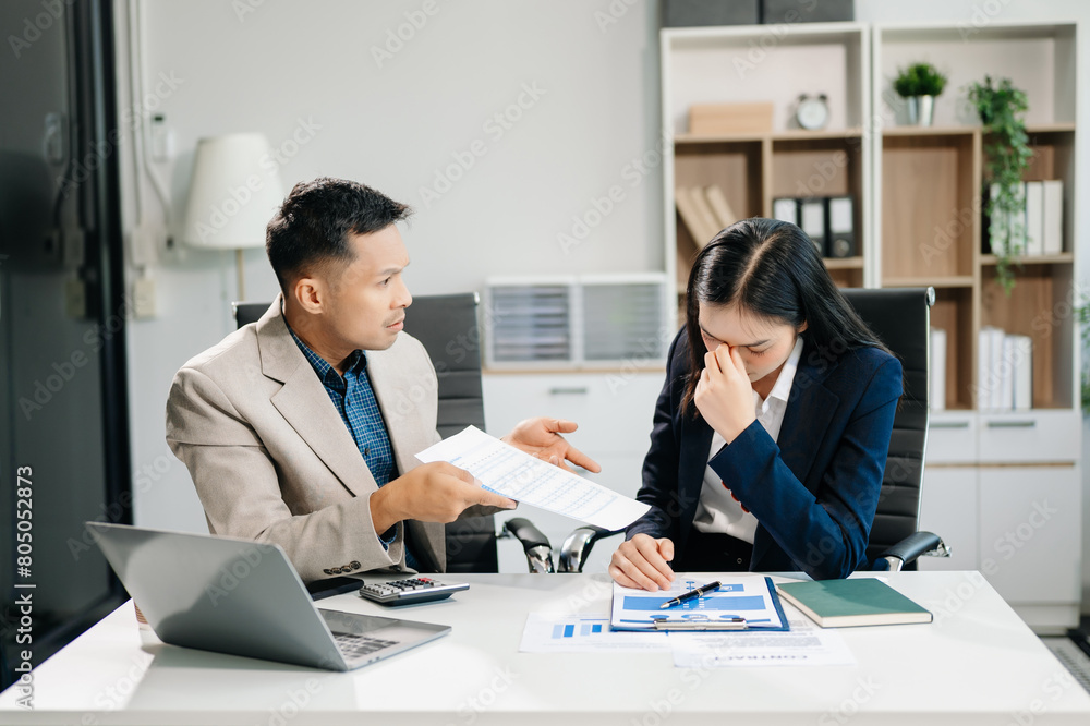 Fototapeta premium Furious two Asian businesspeople arguing strongly after making a mistake at work in modern office
