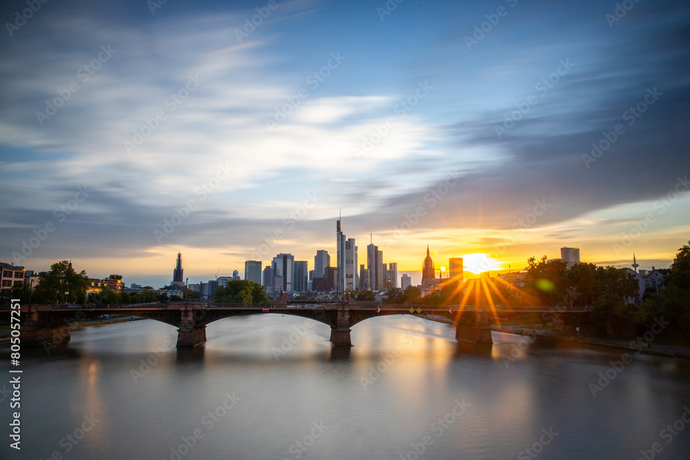View from a bridge over the River Main to a skyline in the financial district in the background as the sun sets. Twilight in Frankfurt am Main, Hesse Germany View from a bridge over the River Main to a skyline in the financial district in the background as the sun sets. Twilight in Frankfurt am Main, Hesse Germany