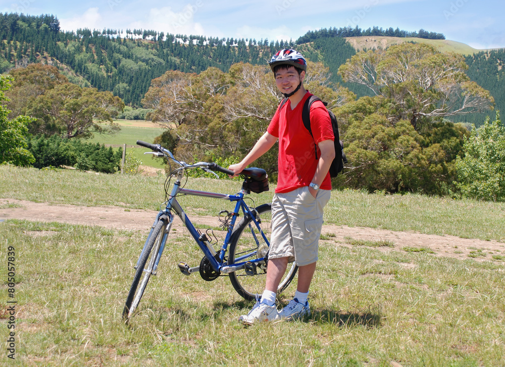 Fototapeta premium Teenage boy with bicycle standing on the hill in autumn. Christchurch.New Zealand.