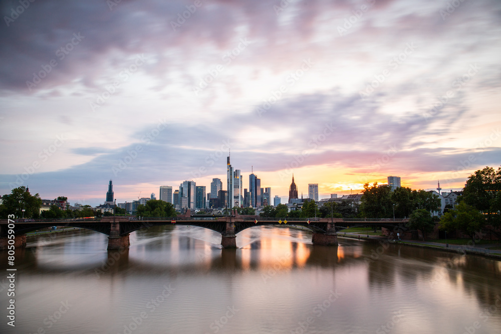 View from a bridge over the River Main to a skyline in the financial district in the background as the sun sets. Twilight in Frankfurt am Main, Hesse Germany