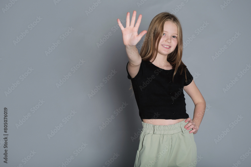 Cheerful girl waving hello, her smile radiating warmth. It s a universal sign of friendship and openness in today s world. Cheerful girl waving hello, her smile radiating warmth. It s a universal sign of friendship and openness in today s world.