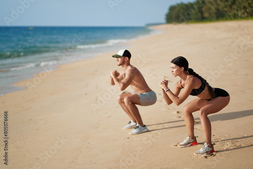 Healthy lifestyle. Young beautiful couple doing sports exercises at the beach.