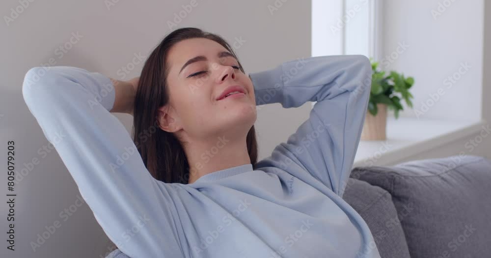 Close up portrait of relaxed young caucasian woman sitting on comfortable sofa in the living room at home having a rest. Peaceful girl enjoying time alone and dreaming. 4k video. Slow motion video. Close up portrait of relaxed young caucasian woman sitting on comfortable sofa in the living room at home having a rest. Peaceful girl enjoying time alone and dreaming. 4k video. Slow motion video.