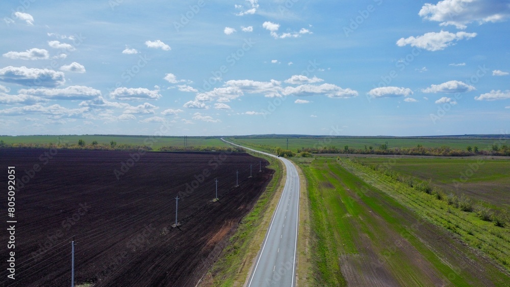 A road passing through empty plowed fields in spring