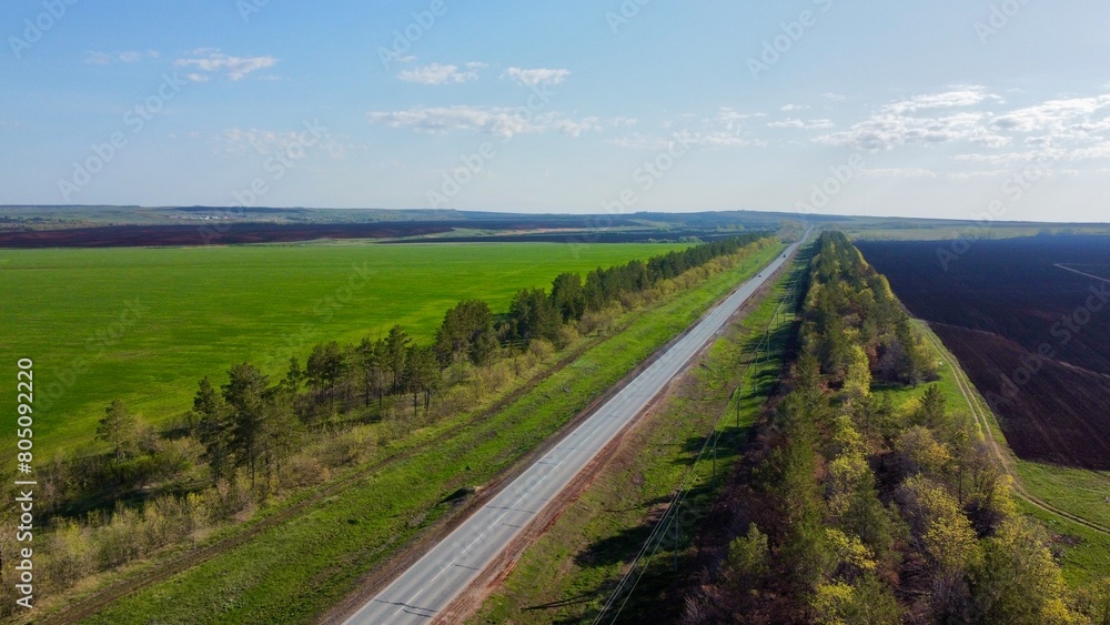 Fototapeta premium A road passing through empty plowed fields in spring