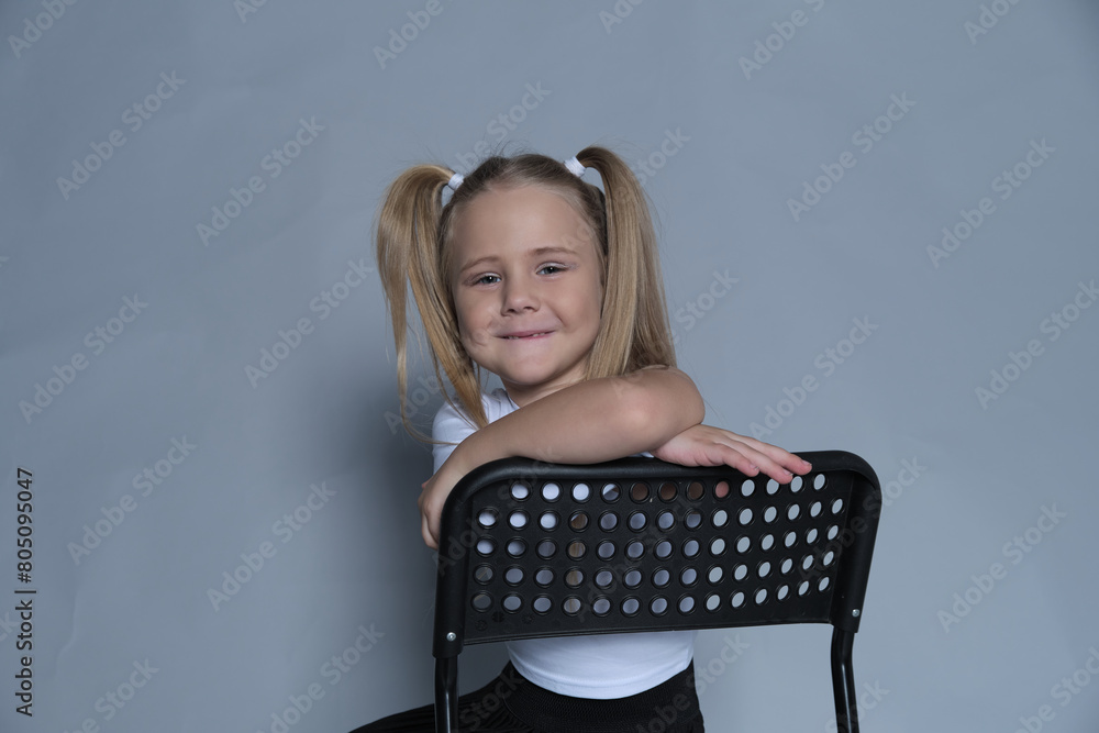 Content child leans on a chair, her joyful smile and lively hairstyle suggesting a moment of playful rest during activities. Content child leans on a chair, her joyful smile and lively hairstyle suggesting a moment of playful rest during activities.