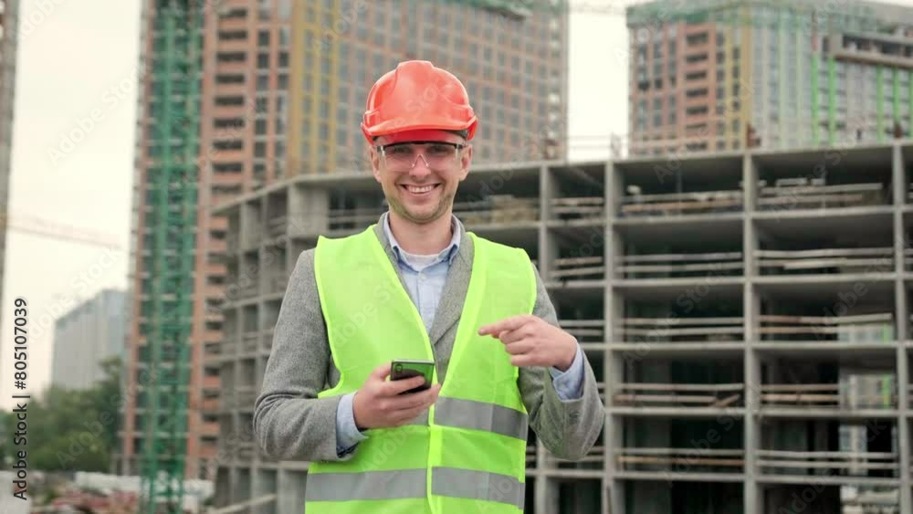 Joyful foreman is posing against background of unfinished multi-story house Joyful foreman is posing against background of unfinished multi-story house