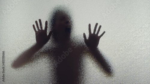 A young woman screams behind the frosted glass