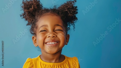 Joyful kid with a 'Smile Day' sign, yellow top and blue backdrop photo