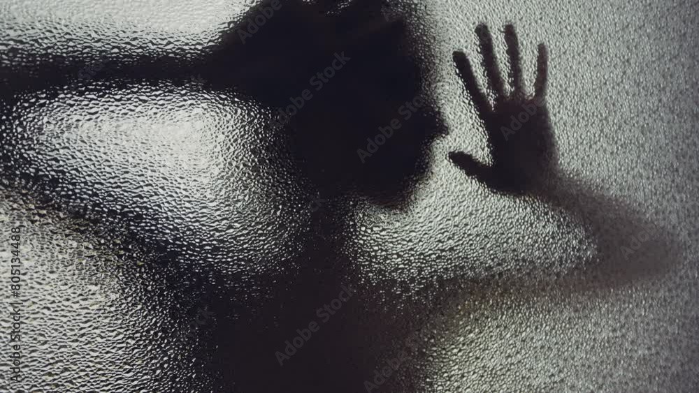 A woman behind the frosted surface puts her hands and face to the glass A woman behind the frosted surface puts her hands and face to the glass