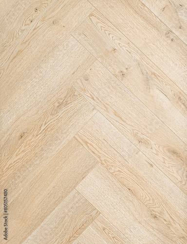 Geringbone pattern laminate in light brown with shades of beige  imitating the texture of natural wood.