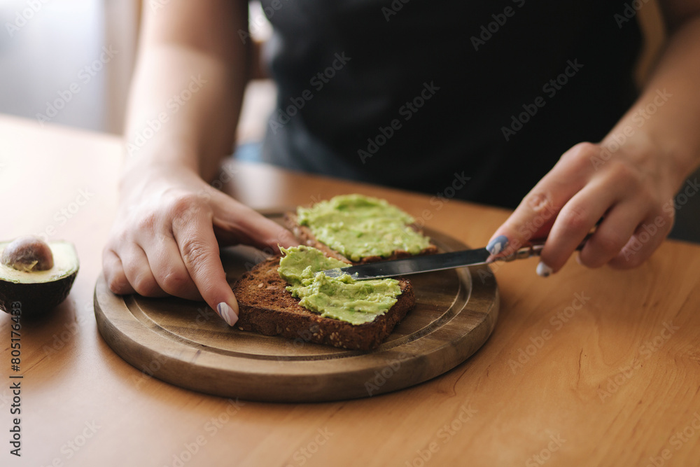 Woman are spreading guacamole on toasted dark bread Woman are spreading guacamole on toasted dark bread