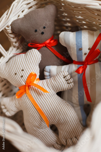 Three handmade teddy bears in a white basket in a child's room. Toys for babies.
