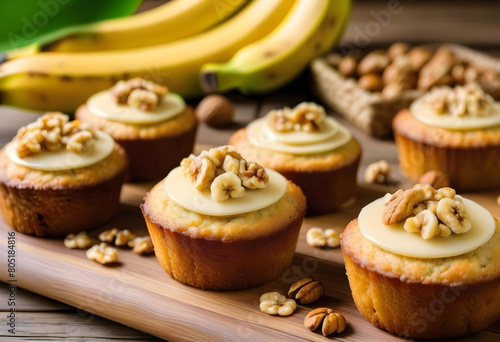A close-up of banana cakes on a wooden tray with bananas and walnuts in the background