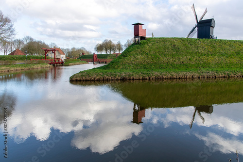 Panoramic view over rampart with mill and canal with reflection of the village of Bourtange (former Fort Bourtange), near Westerwolde the Netherlands; the fortress was built in 1593 shape of a star  photo