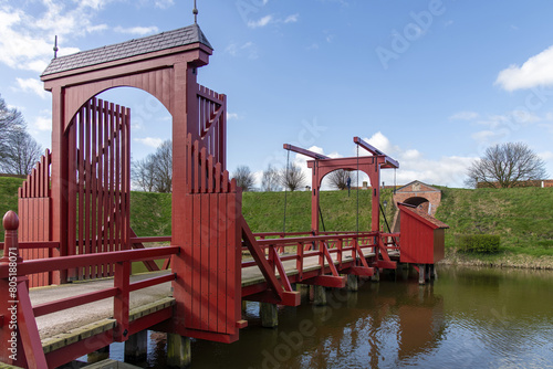 View of canal with bright red bridge and rampart around the village of Bourtange (former Fort Bourtange), near Westerwolde the Netherlands; fortress built in 1593 in shape of a star  photo