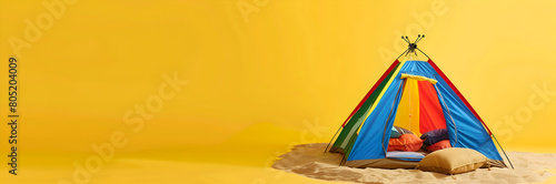 Colorful beach tent with sandbags web banner. Colorful beach tent with sandbags isolated on yellow background with copy space. photo