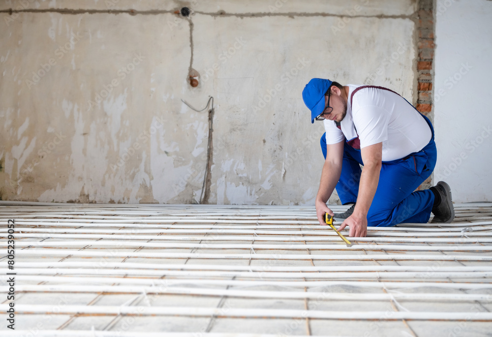 man worker takes measurements during the installation of a warm floor man worker takes measurements during the installation of a warm floor