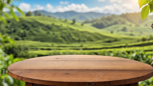 Circle wooden table top with blurred tea plantation landscape against blue sky and blurred green leaf frame for product display