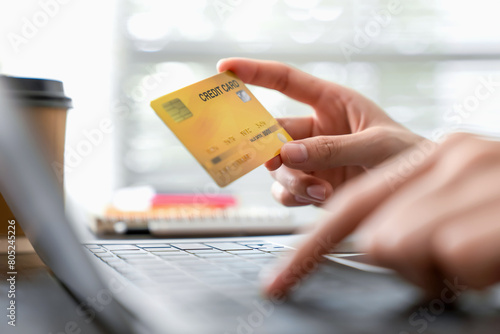 Woman hand holding a credit card and using laptop to pay online. The concept of online shopping and payment.