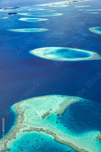 Aerial view or top view of tropical island beach with clear water coral reef. Maldives atolls, nature paradise. Shades of blue, relaxing aerial seascape, landscape. Sunny exotic travel background photo