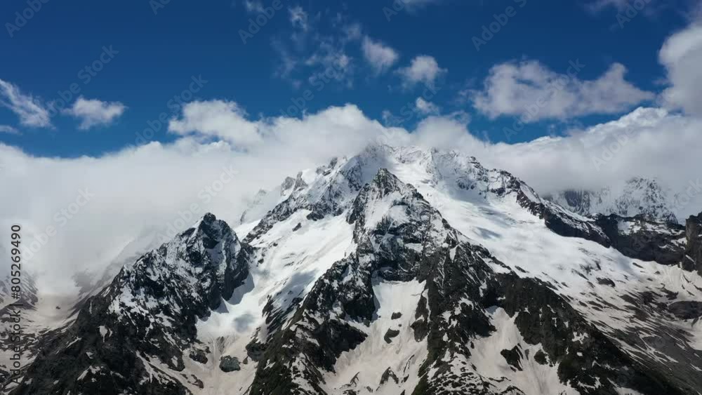 Air flight through mountain clouds over beautiful snow-capped peaks of mountains and glaciers. Air flight through mountain clouds over beautiful snow-capped peaks of mountains and glaciers.