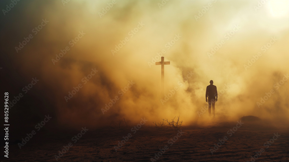 Silhouette of a man in the desert with a cross in the smoke and dust under light the sun, religion concept. 
