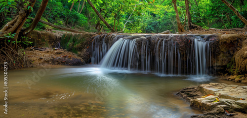 The serene beauty of a small  meandering stream that expands into a breathtaking waterfall  surrounded by the vibrant greens of a tropical jungle. The panorama captures the stream s journey  