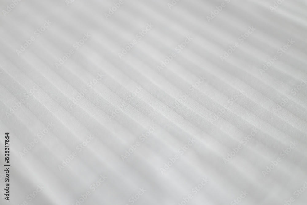 Elegant textile on bed. Striped pattern on a snow-white bedsheet. The manufacturing of bedsheet uses cotton, linen, silk modal and bamboo rayon. Elegant textile on bed. Striped pattern on a snow-white bedsheet. The manufacturing of bedsheet uses cotton, linen, silk modal and bamboo rayon.