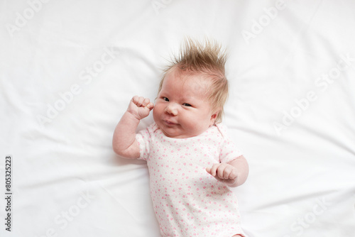 A little newborn Caucasian girl on the white background looking at the camera. Portrait of a 5-week-old baby girl. 