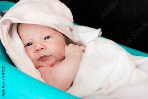Cute adorable newborn baby taking a bath. Tiny girl enjoying warm water and washing. Newborn baby in the bathtub