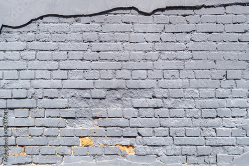 An old brick wall is painted with gray paint. Abstract construction background.