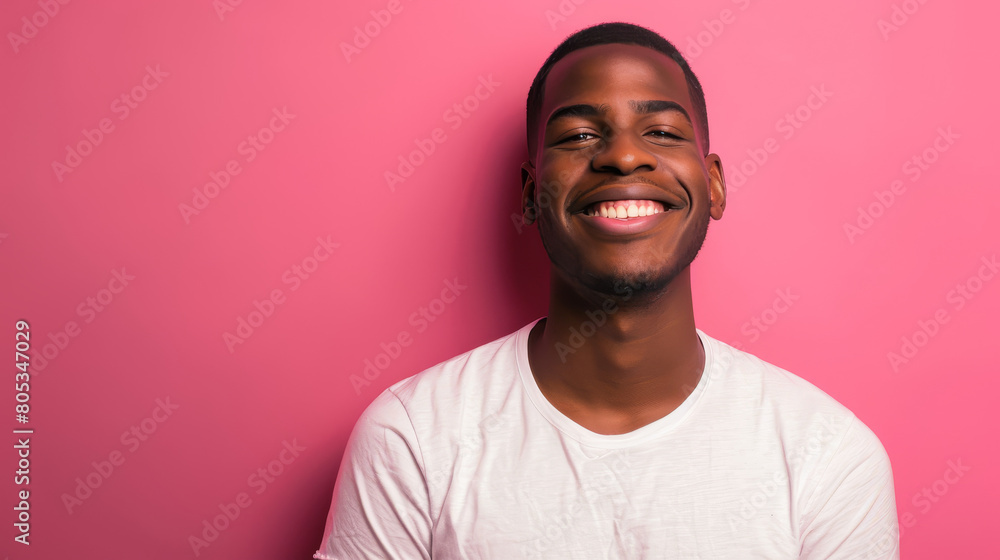 A man with a big smile on his face is standing in front of a pink wall A man with a big smile on his face is standing in front of a pink wall