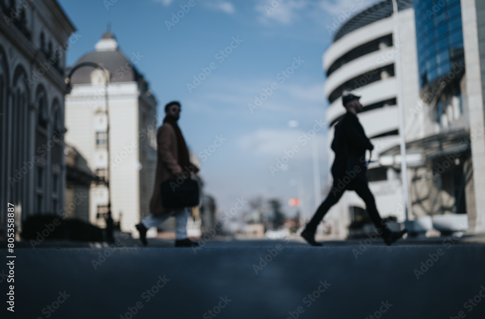 Out of focus shot capturing the hustle of city life with silhouettes of businessmen walking, embodying motion and urban professionalism. Out of focus shot capturing the hustle of city life with silhouettes of businessmen walking, embodying motion and urban professionalism.