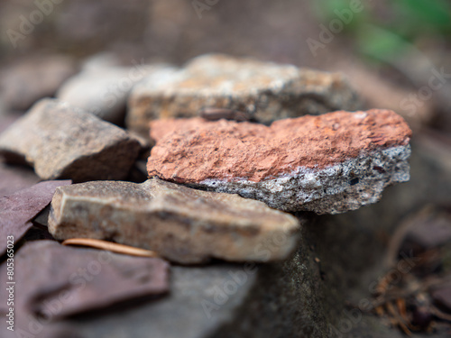 A macro shot of stones with a very narrow plane of focus and in the foreground a red stone that is white blue in the middle and turns brown towards the bottom