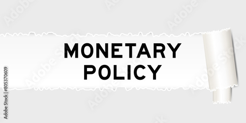 Ripped gray paper background that have word monetary policy under torn part