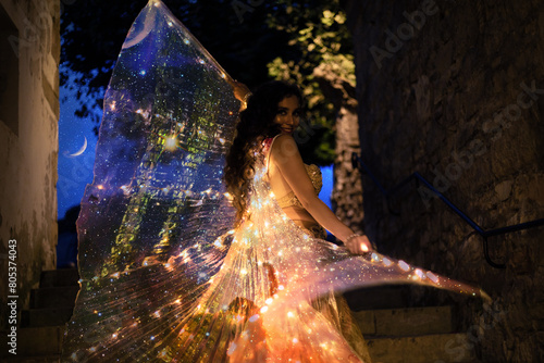 Belly dancer with wings of light under a starry sky	