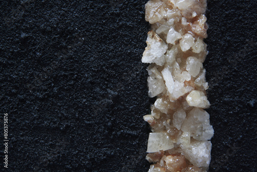 Citrine quartz fragments and black grunge surface, sandy effect. Vertical line of crystals. photo