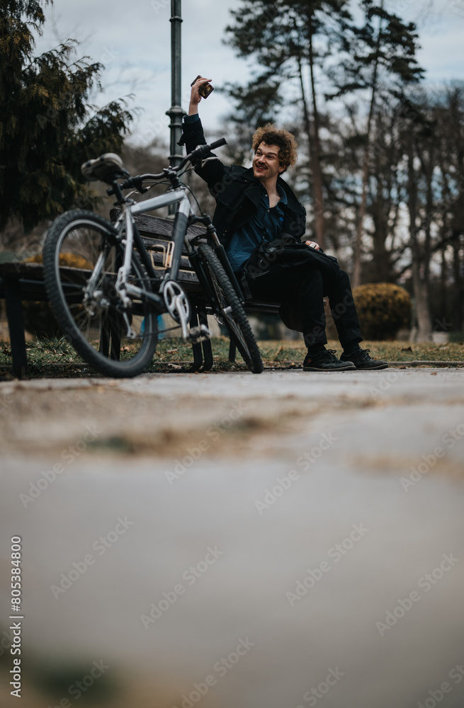 A male businessperson takes a break in the park, working on his notebook next to his bicycle, waving to a friend at the other side. A male businessperson takes a break in the park, working on his notebook next to his bicycle, waving to a friend at the other side.