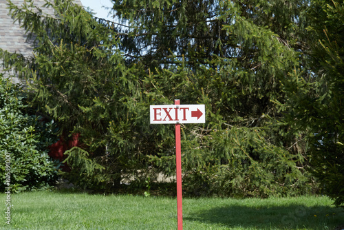 Exit sign with lush green grass and branches in the background. Horrizontal photograph. photo