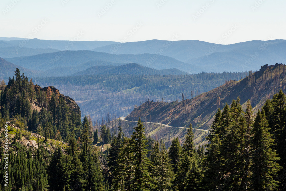 view from the mountains in to the valley of lassen volcanic national park with a beautiful road 