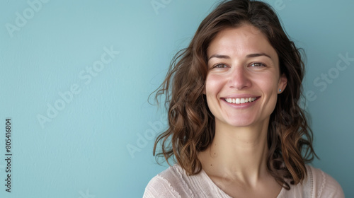A woman with long brown hair is smiling at the camera