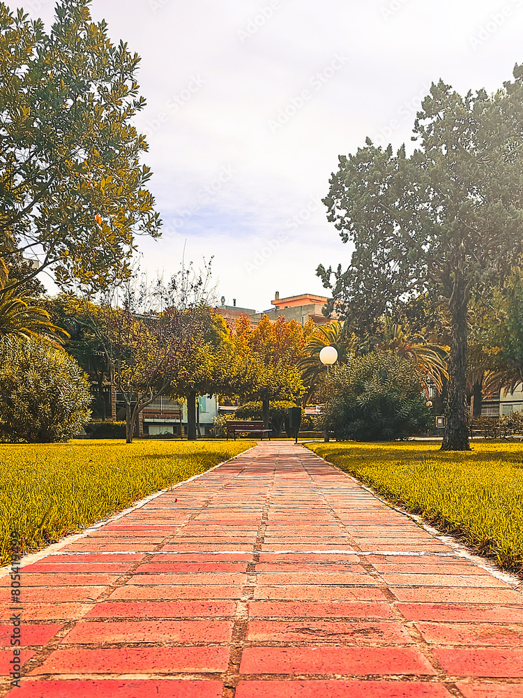 Fototapeta premium Brick road between gardens and trees