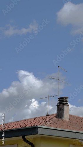 Time lapse, nuvole in movimento, tetto con comignolo e antenna, video verticale photo