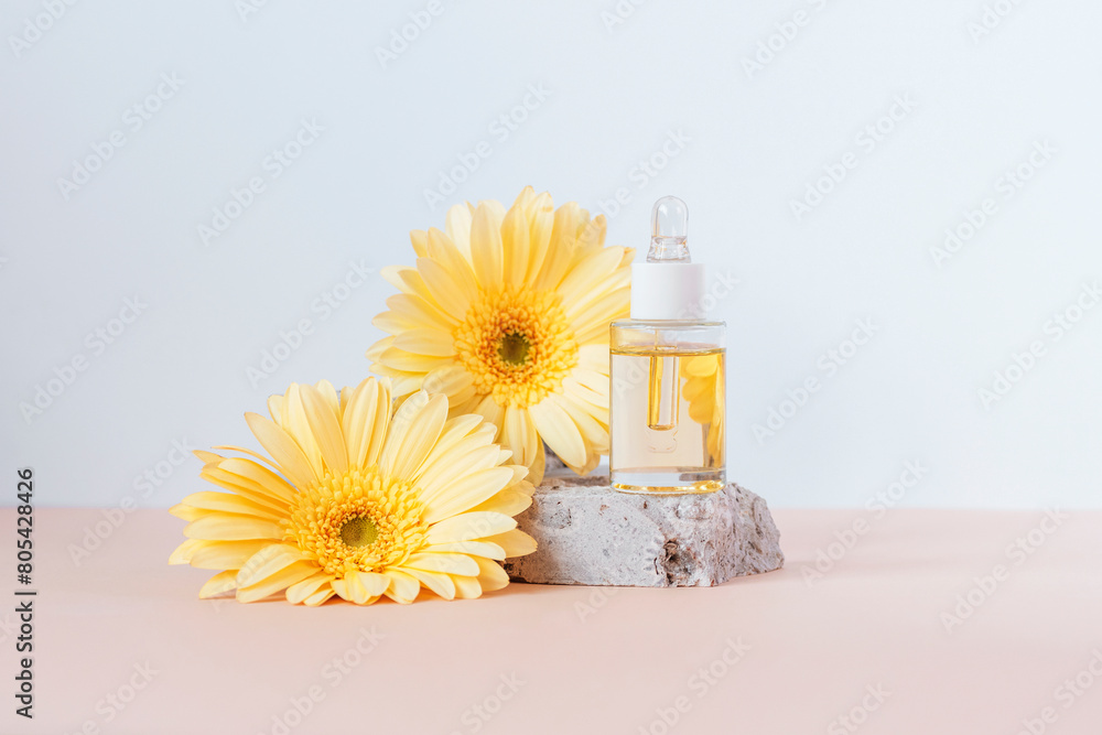 Cosmetic serum bottle on stone podium with yellow gerbera flowers on beige and white background. Front view Cosmetic serum bottle on stone podium with yellow gerbera flowers on beige and white background. Front view