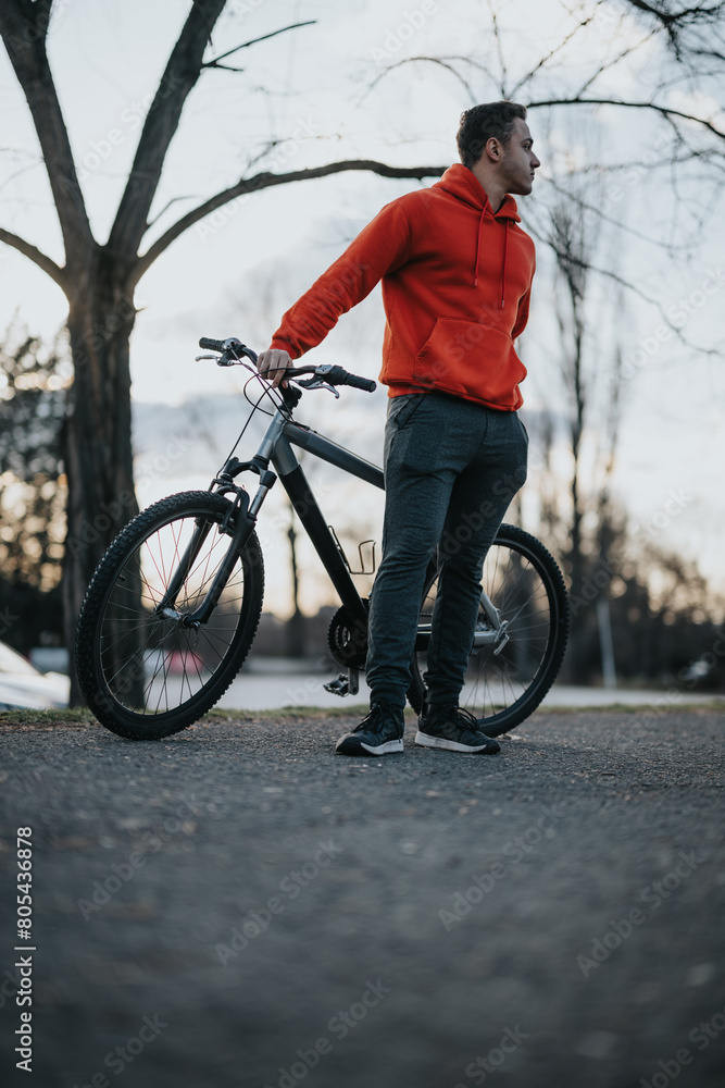 A young, active man standing with his bicycle in an urban park, embodying a healthy and relaxed lifestyle during his free time. A young, active man standing with his bicycle in an urban park, embodying a healthy and relaxed lifestyle during his free time.