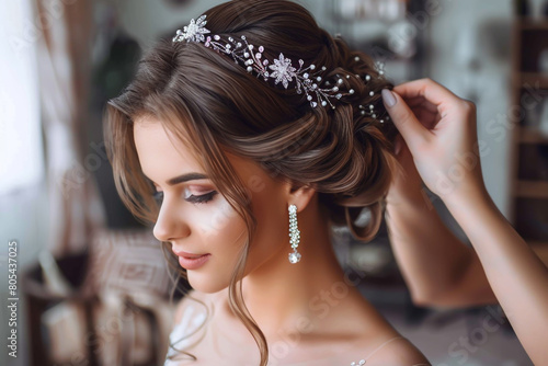 Professional wedding makeup artist doing bride's hairstyle with hair accessories photo