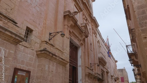 A walking shot showing a statue of the Virgin Mary holding Baby Jesus on the corner of Carmelite Priory in Mdina, Malta photo