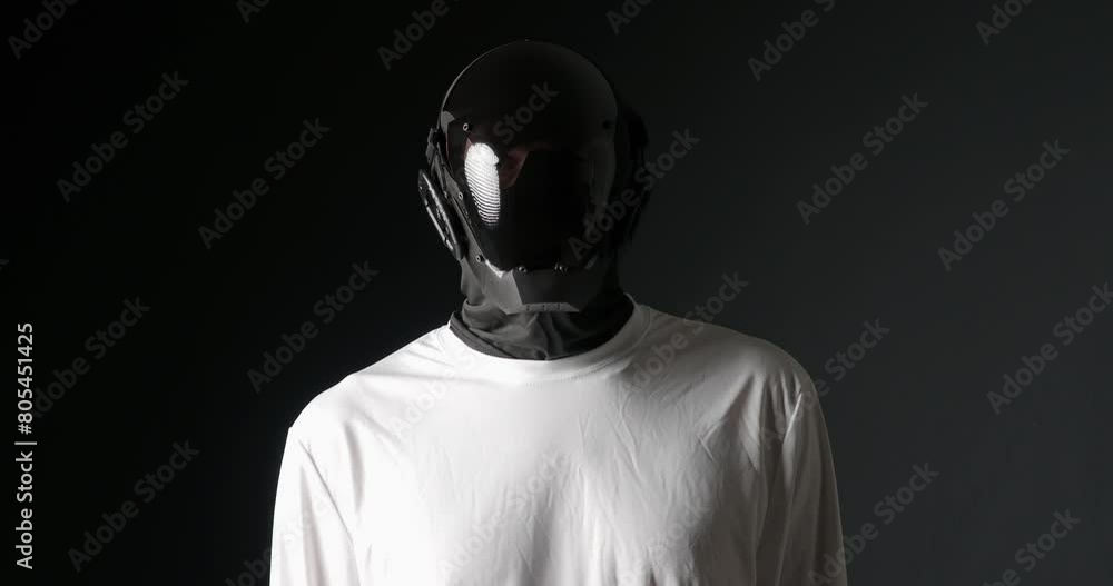 Unrecognizable man in black robot mask, looking around. Unrecognizable man in black robot mask, looking around.